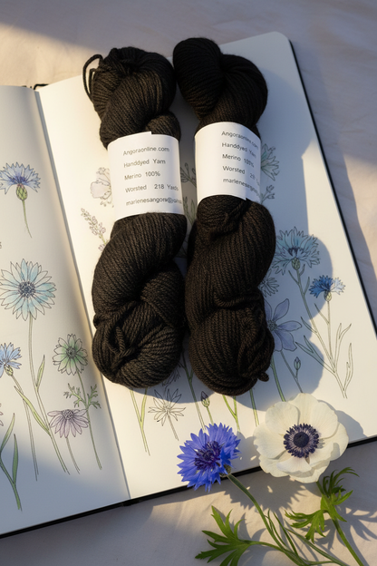 Black merino yarn skeins on wildflower sketchbook with blue and white flowers